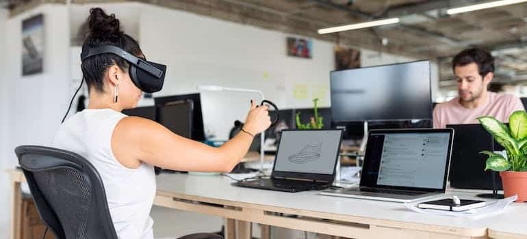 A woman using a VR set and laptop computers.