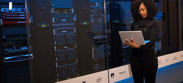 Big data engineer standing besides server racks, doing one of the high-paying IT jobs