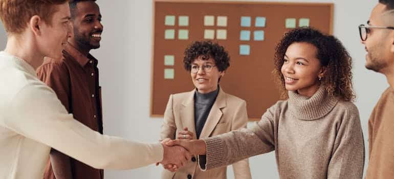 A company representative shaking hands with a full-stack developer while hiring them