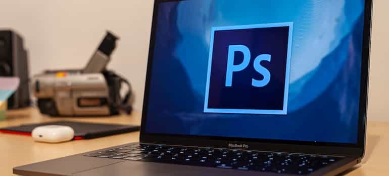 MacBook with Adobe Photoshop logo on the screen.