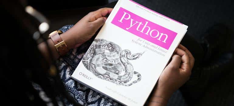 A woman holding a book of the best Python libraries for machine learning
