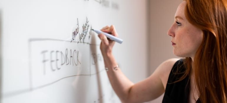 A woman writing on a whiteboard - a word 'feedback', as one of the top  software testing strategies